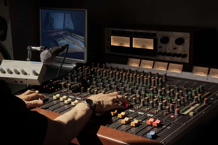 Man operating a mixing console with microphone and monitor