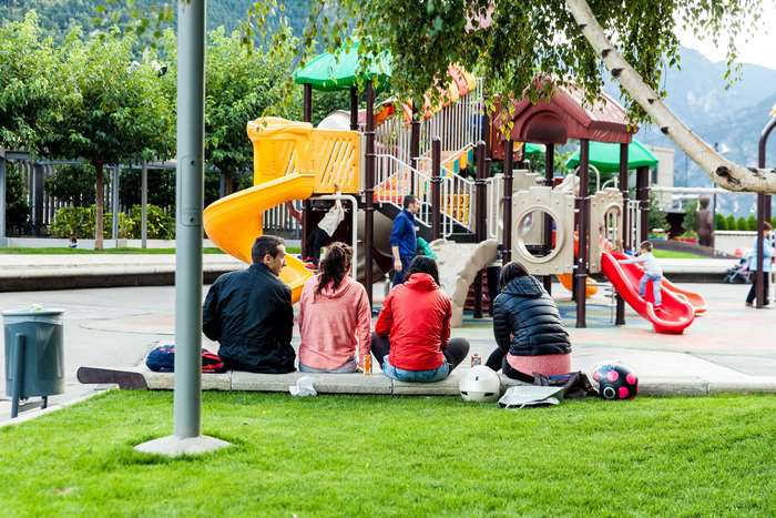 People sitting at a playground with mountains in the background