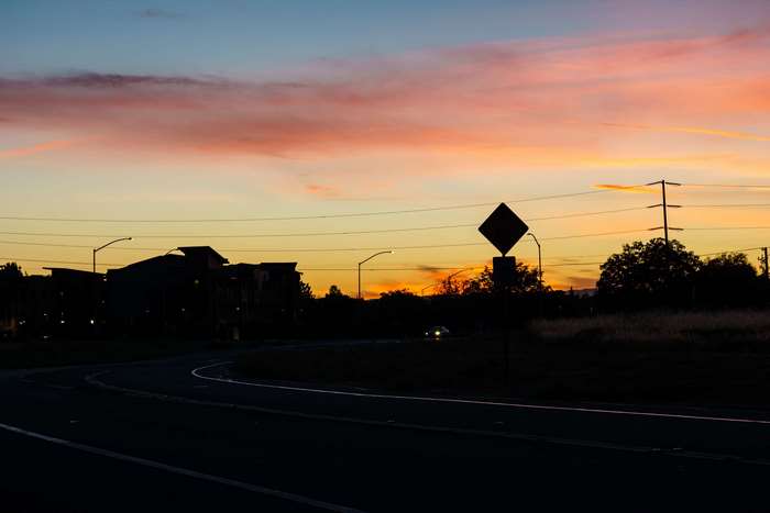 Sunset over suburban road with power lines
