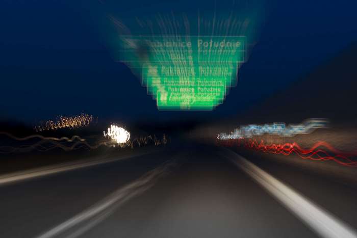Night highway with motion blur and green sign