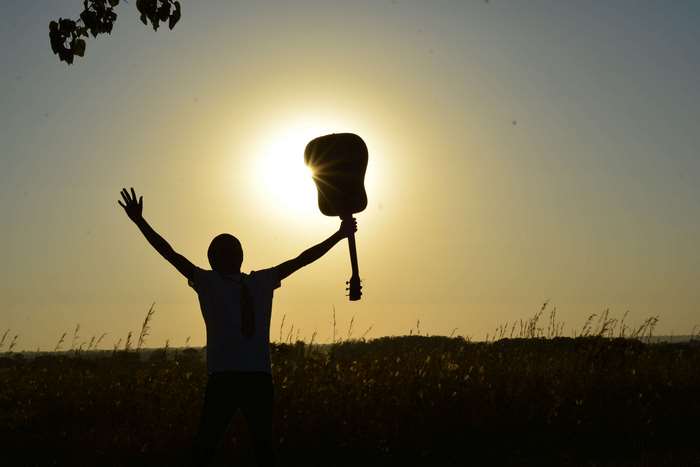 Silhouette of a musician holding a guitar at sunset