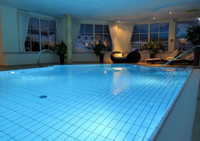 Indoor swimming pool with lounge chairs and large windows