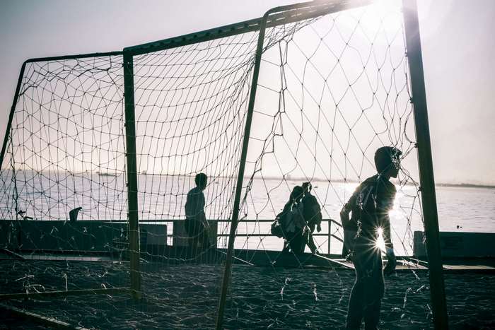 People playing soccer on a beach near the sea