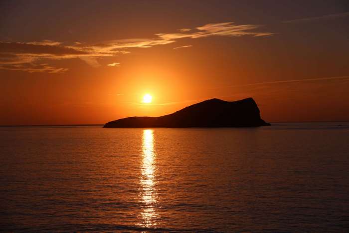 Sunset over the sea with an island and light reflections