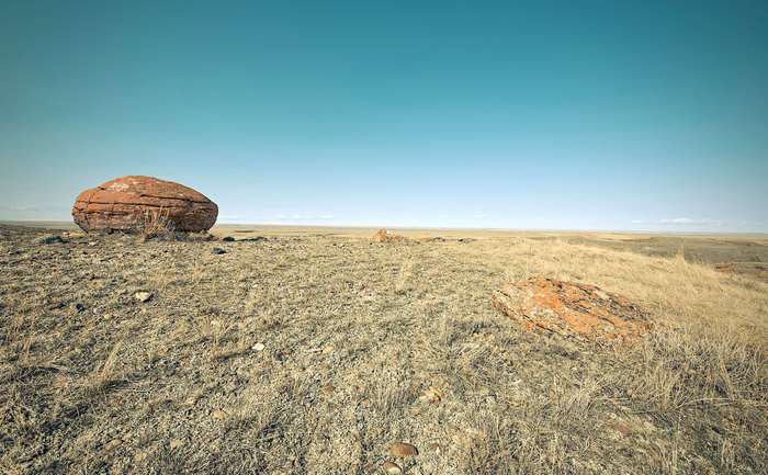Red rock on a dry grassy hill under a blue sky