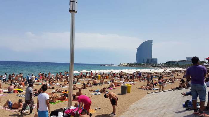 Barcelona beach with people sunbathing and Hotel W in background