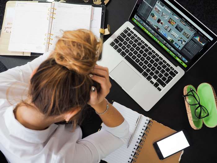 Woman stressed at desk with laptop and planner 4K