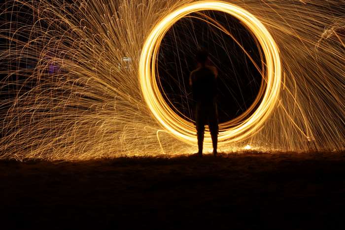 Person creating a circle of fire sparks at night