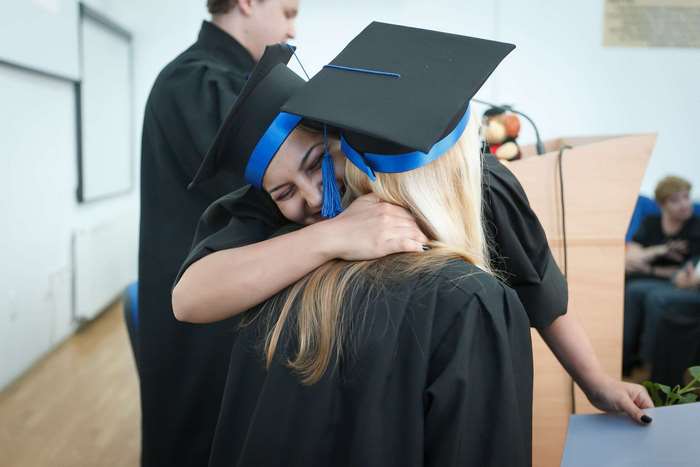 Graduates hugging at a graduation ceremony