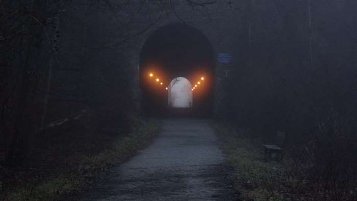 Dark train tunnel with lights on a foggy morning