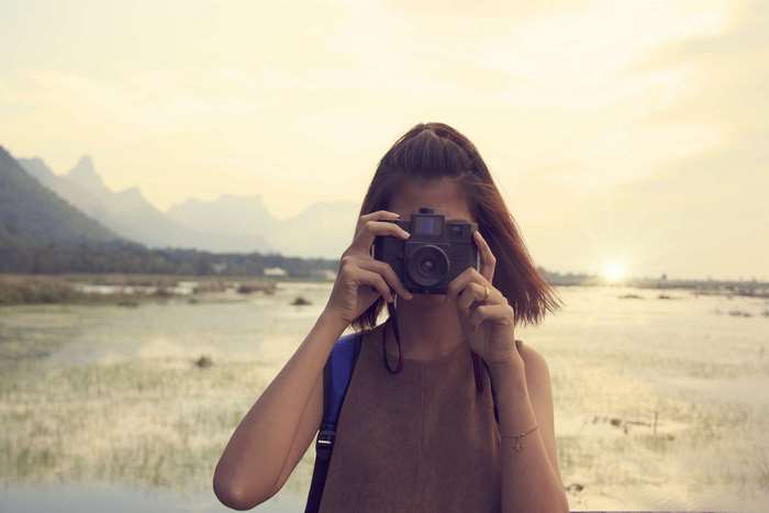 Woman taking a photo with a camera at sunset