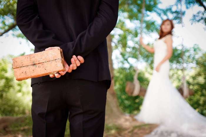 Groom hiding a brick behind his back from bride