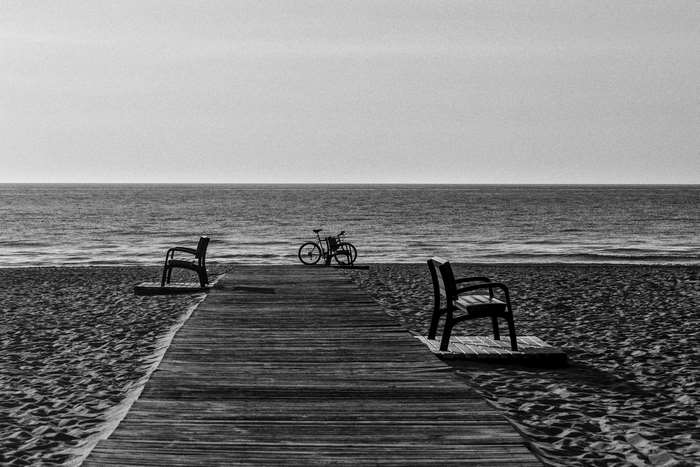 Black and white beach scene with benches and bicycle