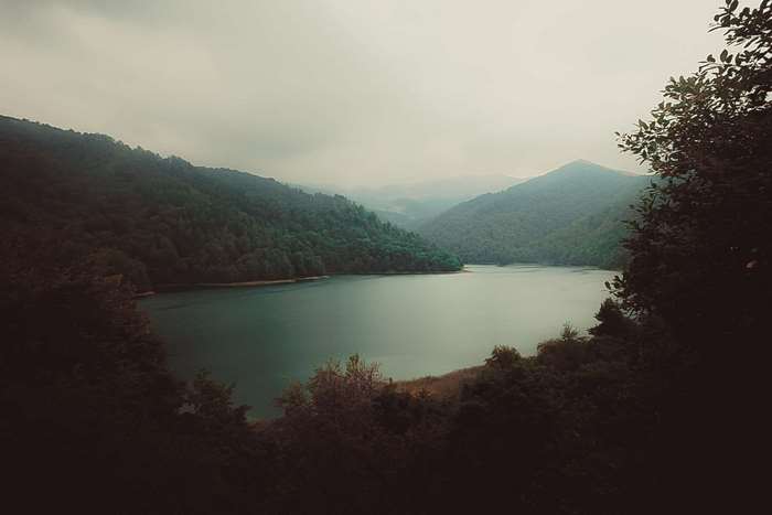 Overcast day over a forest lake and mountains