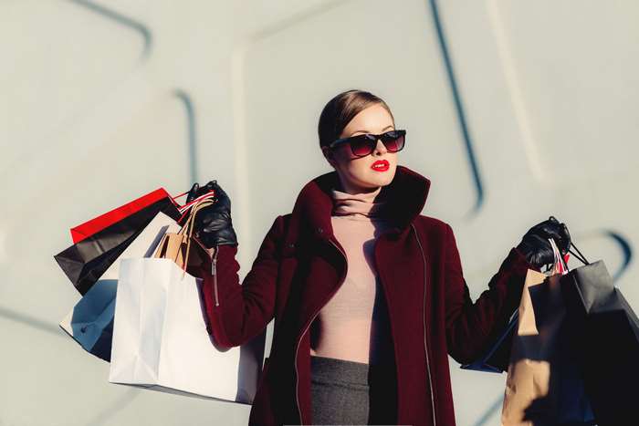 Woman in sunglasses and coat with shopping bags