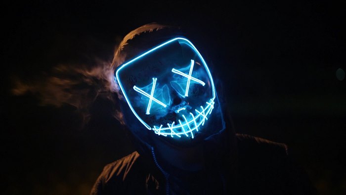 Person wearing a blue neon mask at night