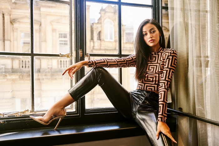 Fashionable woman posing by window in stylish outfit 4K