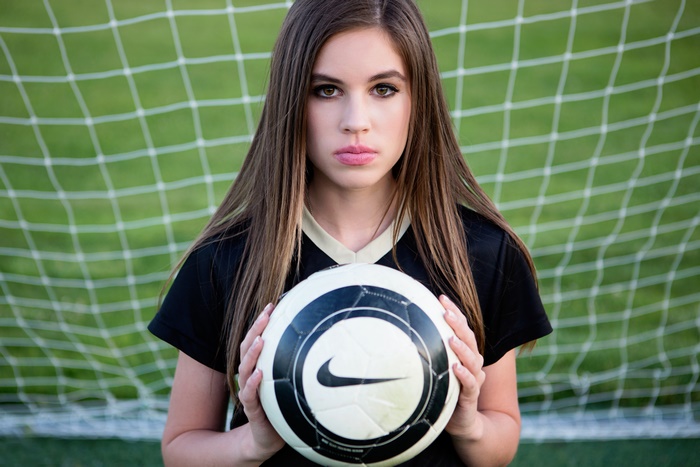 Girl holding a Nike soccer ball in front of a goal