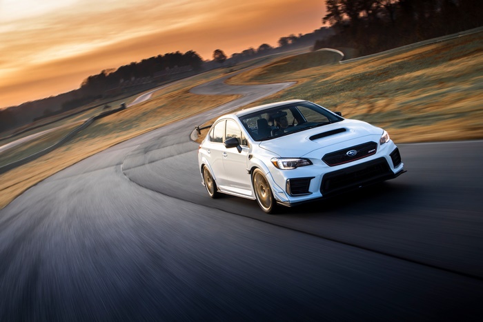 White Subaru WRX STI on a race track at sunset