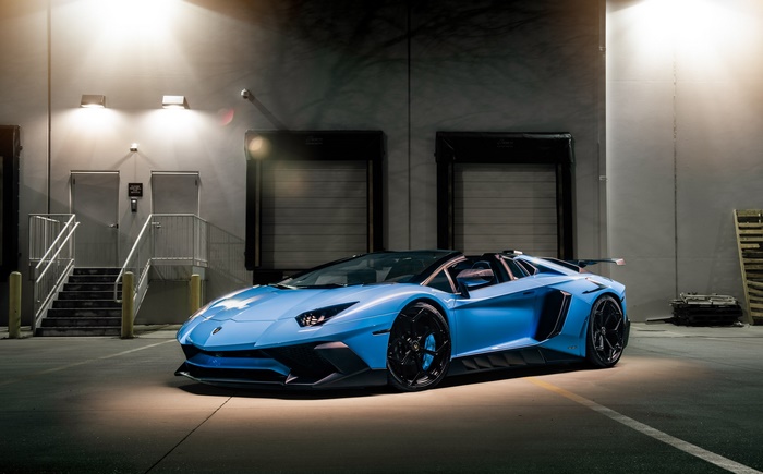 Blue Lamborghini Aventador SVJ Roadster parked outside warehouse
