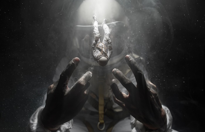 Astronaut floating in space with hands reaching out