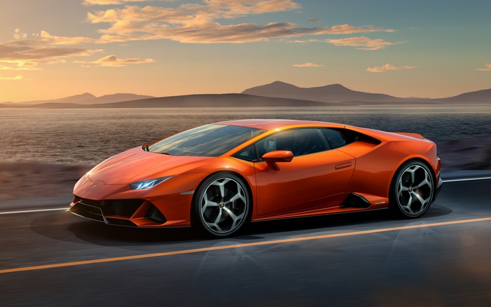Orange Lamborghini Huracan driving on a road by the sea