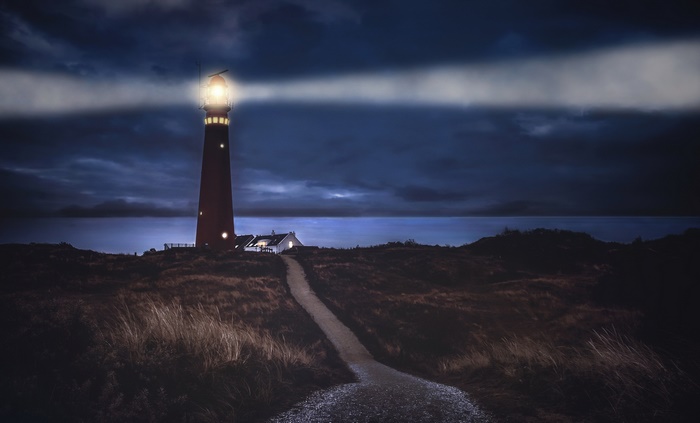 Lighthouse shining light on the sea at night