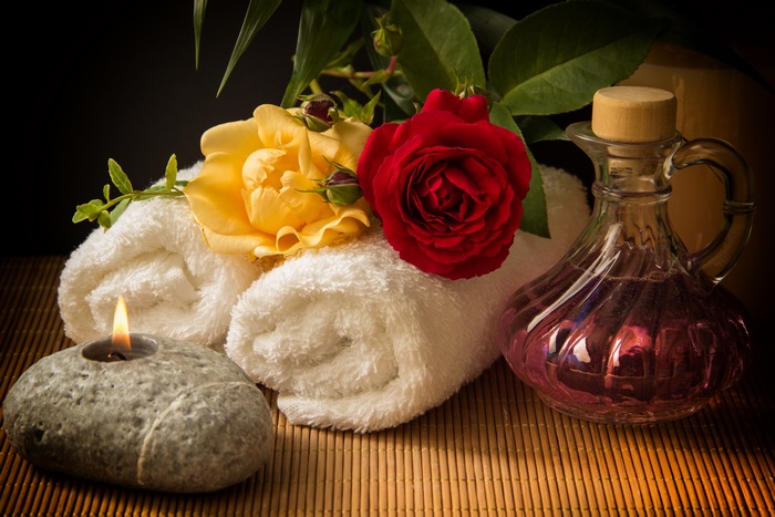 Spa still life with roses, candle, and oil bottle