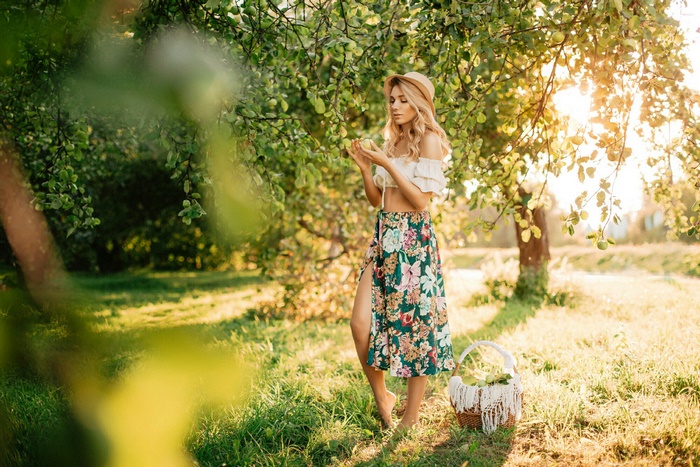 Blonde Woman in Floral Skirt Standing in Sunlit Garden
