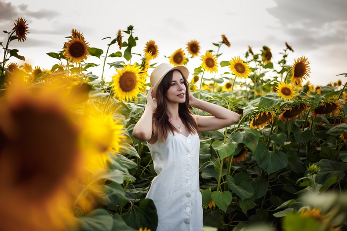 Woman in white dress and hat in sunflower field