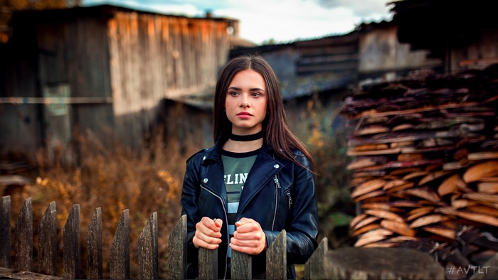 Woman in leather jacket standing behind a fence