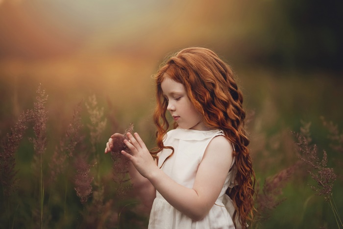Little girl with long red hair in a field