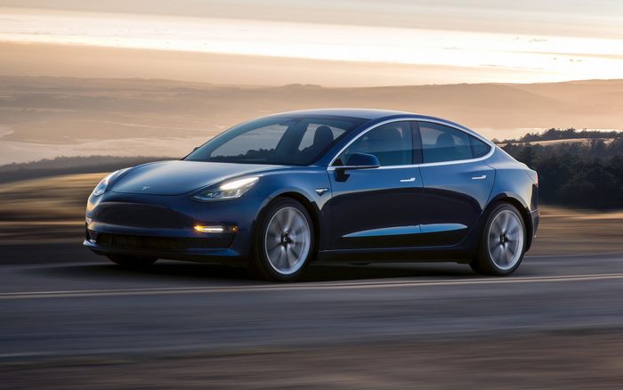 Blue Tesla Model 3 driving on a road