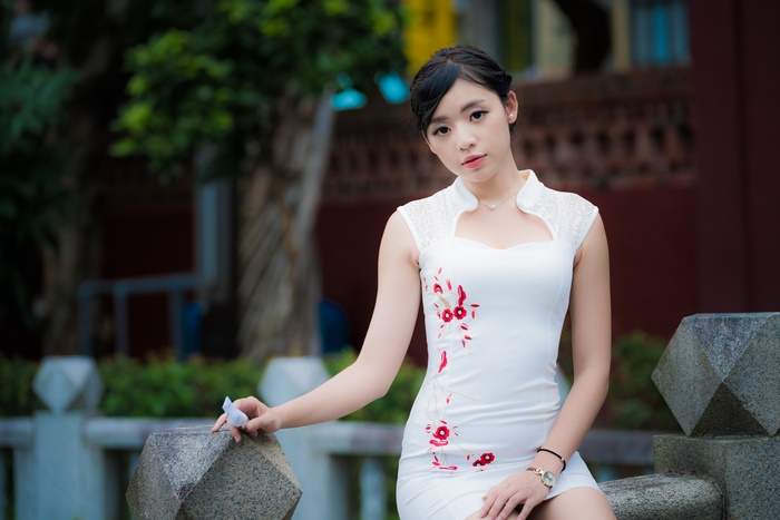 Asian woman in white dress with red floral embroidery