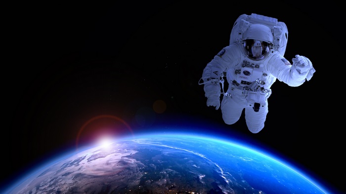 Astronaut floating above Earth during sunrise