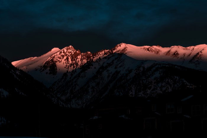 Snowy mountains at sunset with dark sky