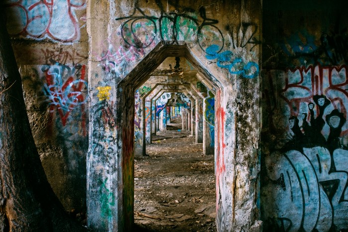 Graffiti-covered abandoned concrete corridor with arches