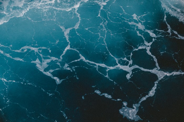 Abstract blue ocean water with white foam texture
