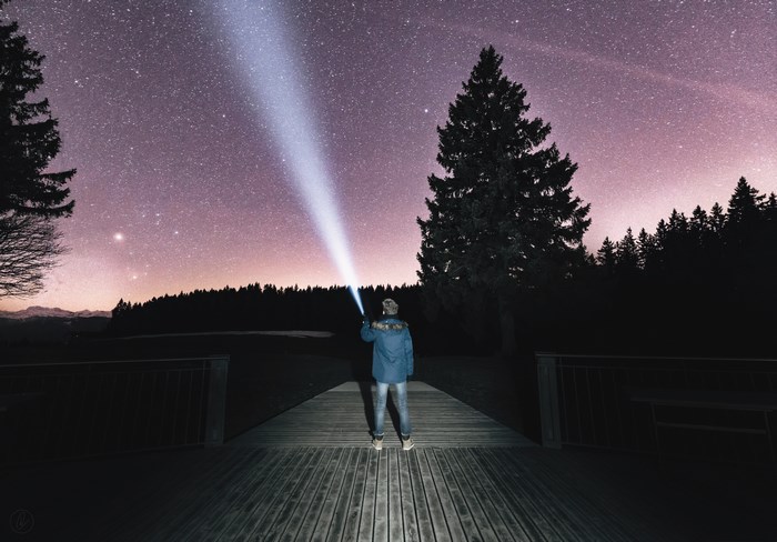 Man with flashlight under starry night sky