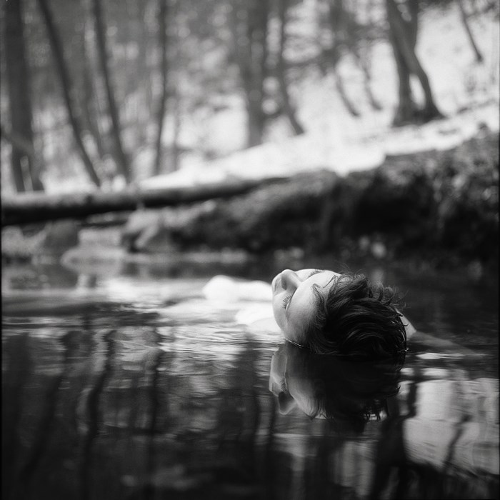 Woman floating in water in a forest