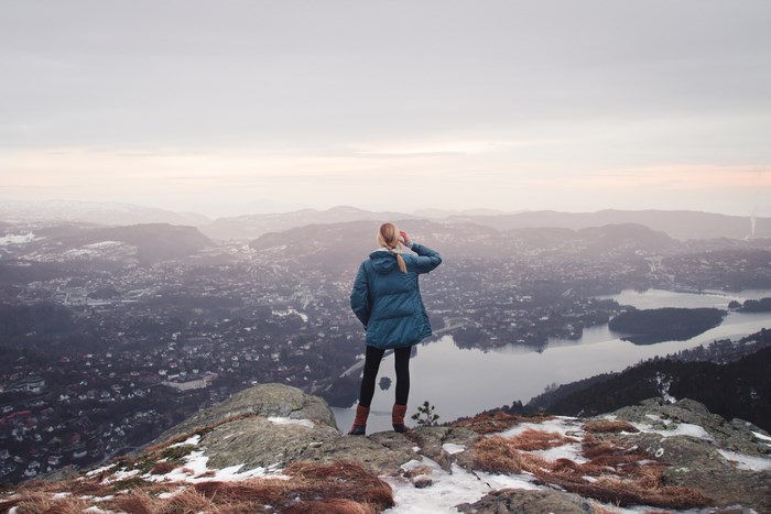 Woman on mountain top overlooking city and lake
