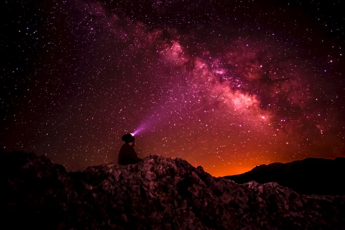 Person with headlamp looking at the Milky Way galaxy