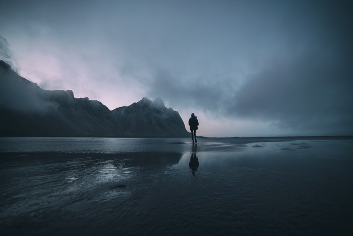 Person walking on a misty beach with mountains