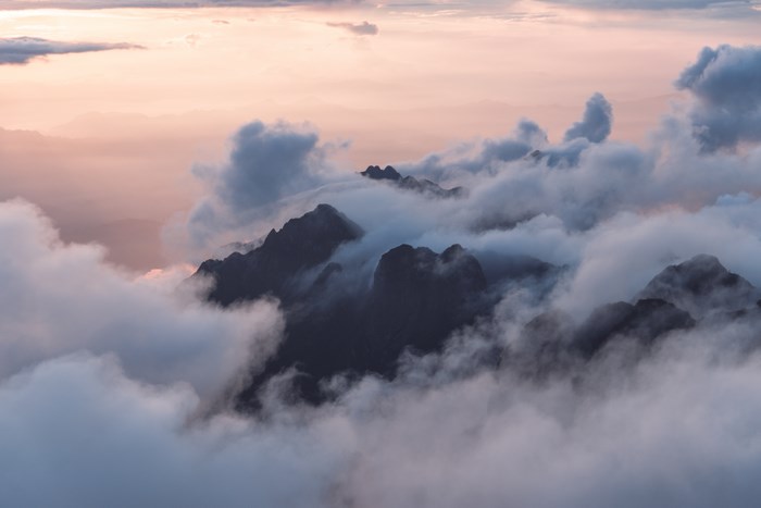 Mountain peaks shrouded in clouds at sunset