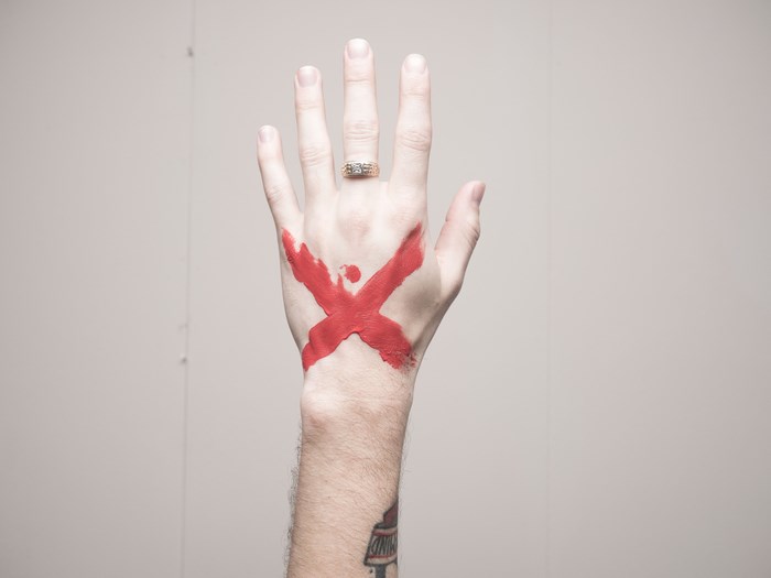 Hand with red X paint and ring