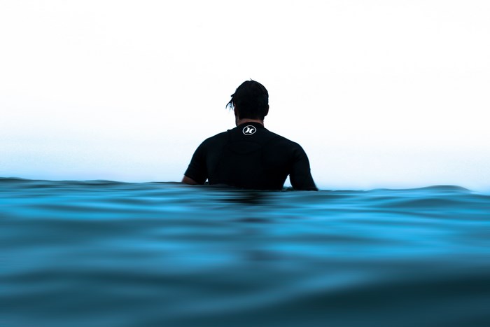 Man in wetsuit sitting in the ocean
