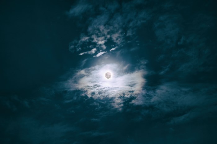 Full moon obscured by clouds at night