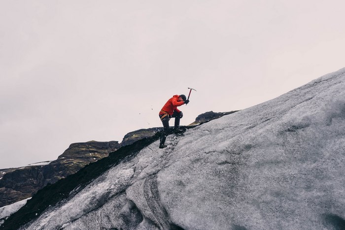 Man climbing a glacier with an ice axe