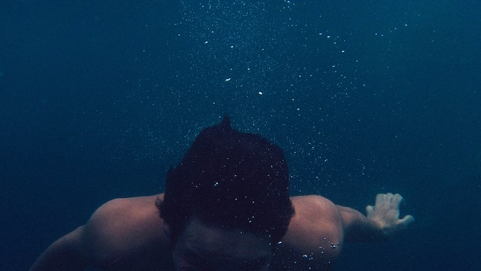 Man swimming underwater with bubbles