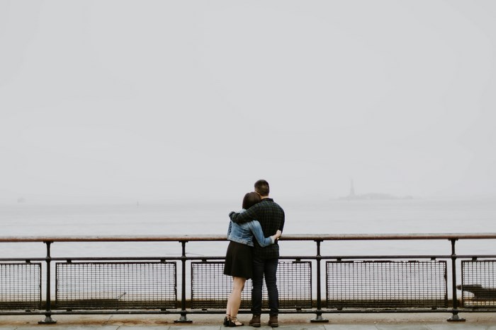Couple embracing on a pier overlooking a foggy bay